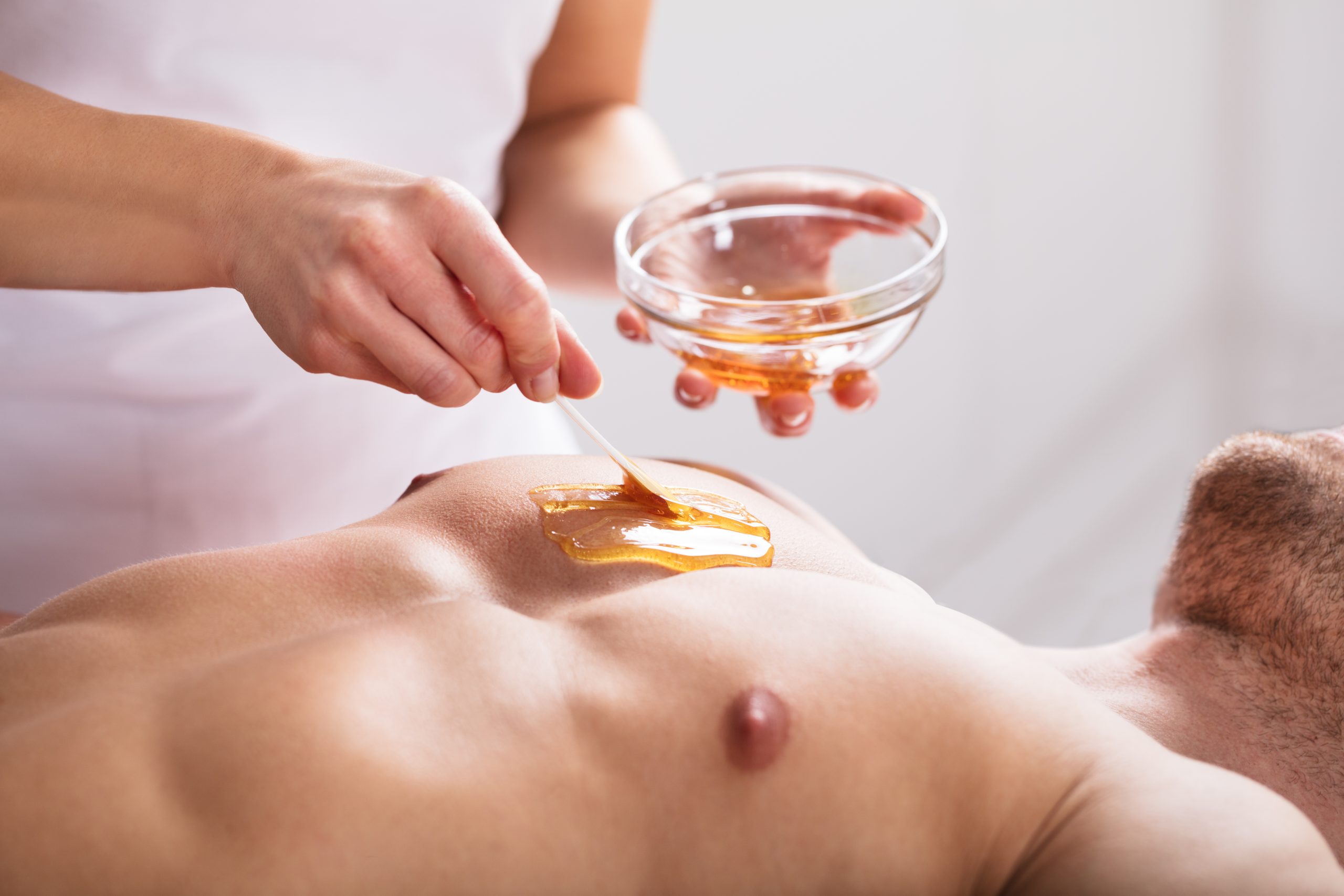 therapist applying wax on man's body